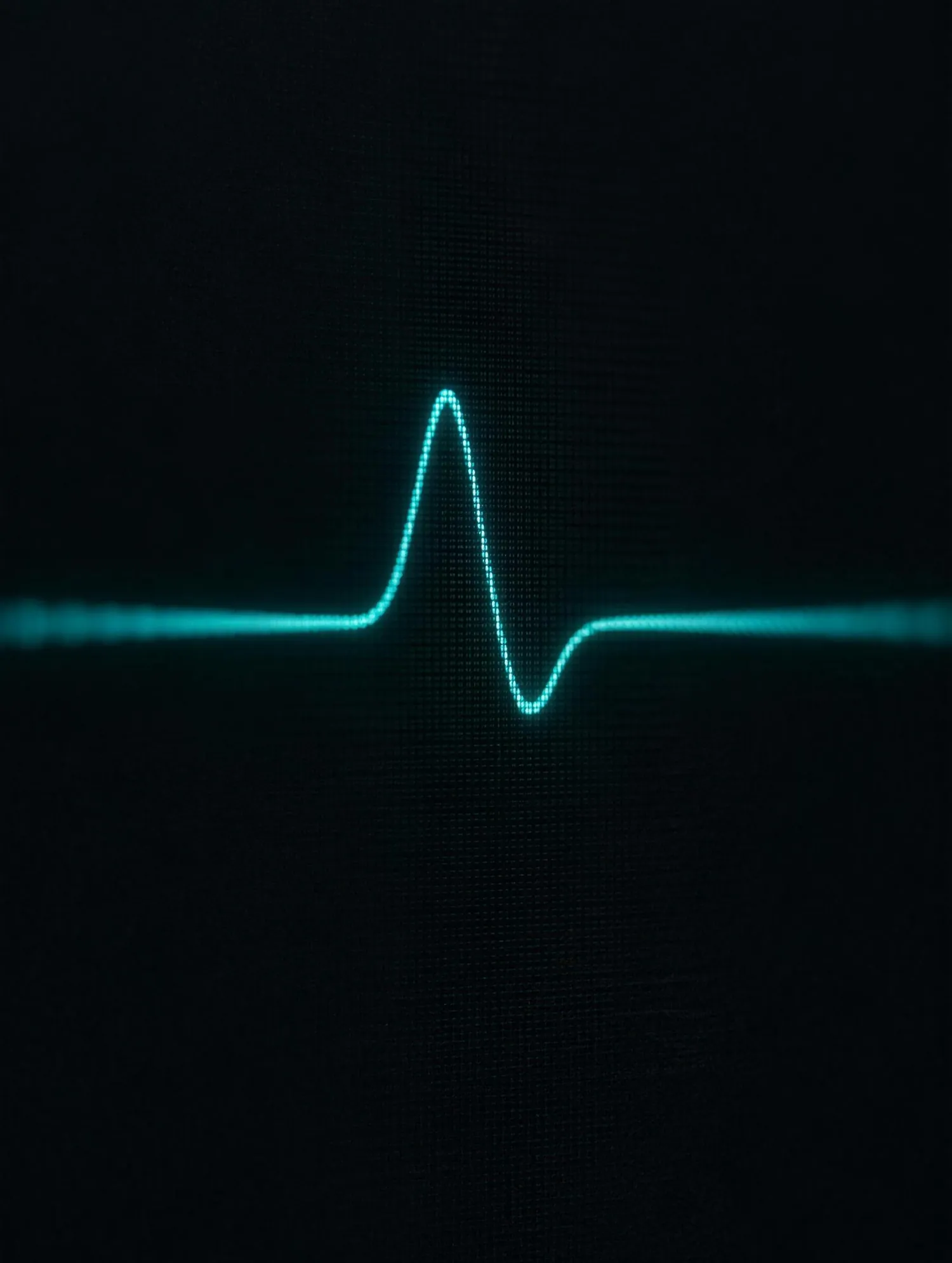 A single evoked muscle response traced in teal on a dark monitor screen